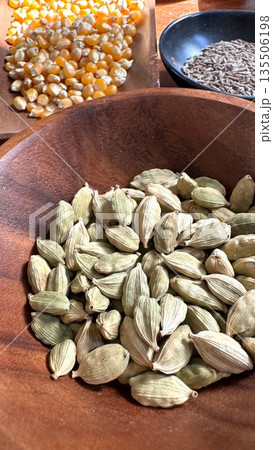 Wooden Dish Showcasing Aromatic Green Cardamom Pods In Rustic Setting, Charming Farm Style Scene Featuring Bowl Of Fragrant Green Spice Pods On Weathered Wooden Surface Wooden Dish Showcasing Aromatic Green Cardamom Pods In Rustic Setting, Charming Farm Style Scene Featuring Bowl Of Fragrant Green Spice Pods On Weathered Wooden Surface 135506198