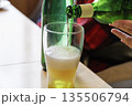 緑のボトルからグラスに注がれる黄金色のビールと泡立つグラス 135506794