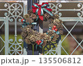 アンティーク風の鉄製門扉に飾られた松ぼっくりのクリスマスリース 135506812