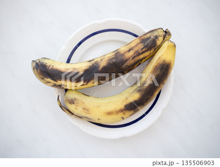Overripe banana in a plate on a marble background. Overripe banana in a plate on a marble background. 135506903