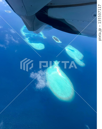A plane is flying over the ocean and the water is blue 135507117