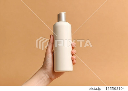 Hand holding white bottle of shampoo or hair conditioner on beige background, copy space Hand holding white bottle of shampoo or hair conditioner on beige background, copy space 135508104