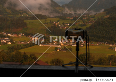 Scenic landscape view captured by camera on tripod overlooking lush green valley at sunset Scenic landscape view captured by camera on tripod overlooking lush green valley at sunset 135509024