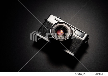 暗い背景にスポットライトが当たった古いフィルムカメラ 暗い背景にスポットライトが当たった古いフィルムカメラ 135509619