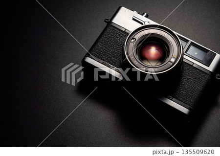 暗い背景にスポットライトが当たった古いフィルムカメラ 暗い背景にスポットライトが当たった古いフィルムカメラ 135509620