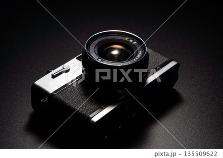 暗い背景にスポットライトが当たった古いフィルムカメラ 135509622