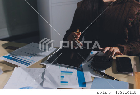 Close-up of businessman's hands making notes, mobiles, chart, desk, office Close-up of businessman's hands making notes, mobiles, chart, desk, office 135510119