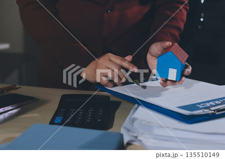 Customer signing a real estate contract in real estate agency. 135510149