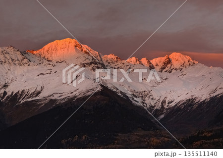 The mountains are covered in snow and the sun is setting behind them The mountains are covered in snow and the sun is setting behind them 135511140