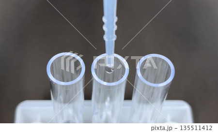 プラスチック試験管3本にスポイトで液体を滴下する医療・検査・実験シーンのクローズアップ 135511412