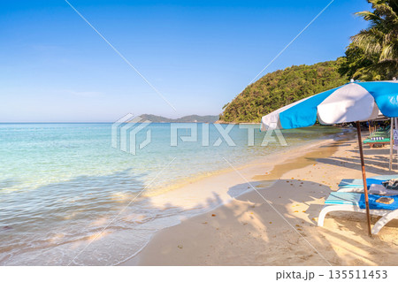 Blue and white beach umbrella with sun loungers on the sunny shore of Ao Prao, Koh Samed, Rayong, Thailand 135511453