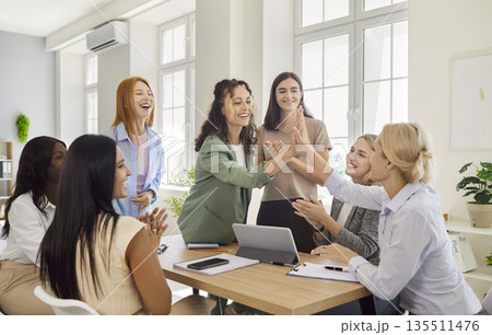 Women give high five, colleagues applaud teamwork achievement on meeting in office 135511476