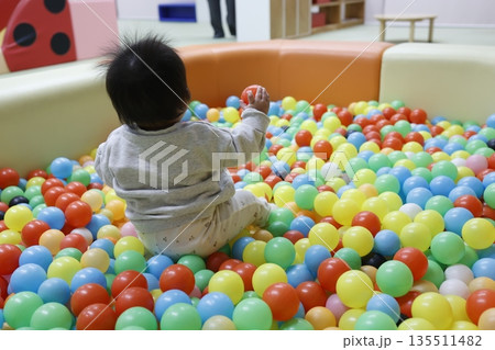 ボールプールで遊ぶ0歳児の後ろ姿。室内遊び。 ボールプールで遊ぶ0歳児の後ろ姿。室内遊び。 135511482