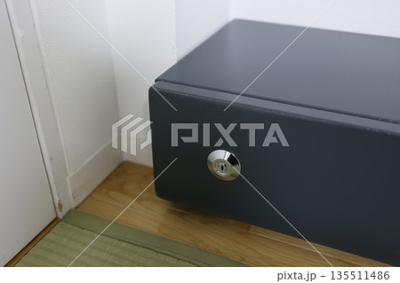 畳の和室に設置された黒い家庭用金庫。 135511486