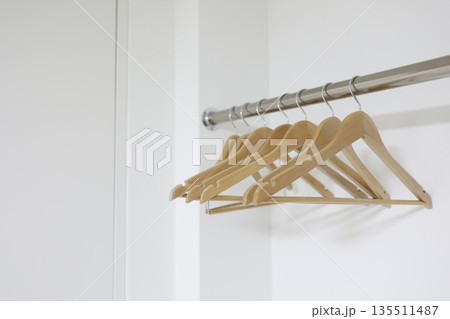 白を基調とした空のクローゼットと複数の木製ハンガー。 135511487