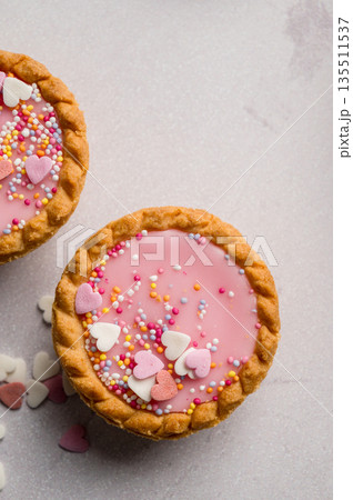 Valentine's day dessert. Pink mini tarts with heart shaped sprinkles. Top view 135511537