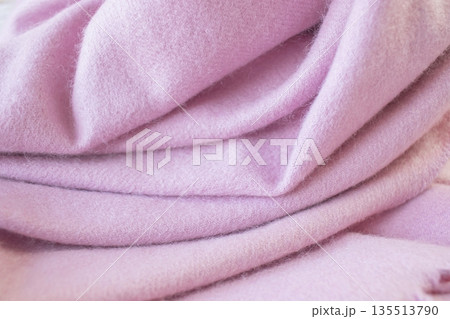 Pale pink cashmere scarf with fringe around the edge. Soft pink draped fabric texture. 135513790
