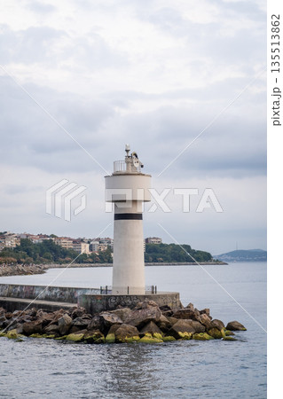 A lighthouse on the Bosphorus stands along the rocky shoreline, surrounded by calm waters under a cloudy sky, showing the beauty of this iconic location. A lighthouse on the Bosphorus stands along the rocky shoreline, surrounded by calm waters under a cloudy sky, showing the beauty of this iconic location. 135513862