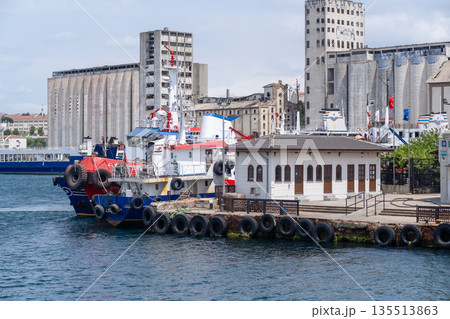 Boats are docked along the Bosphorus waterfront beside old buildings, illustrating vibrant city life and maritime activities in Istanbul during a sunny day. Boats are docked along the Bosphorus waterfront beside old buildings, illustrating vibrant city life and maritime activities in Istanbul during a sunny day. 135513863