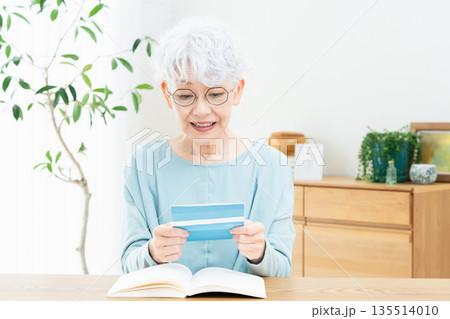 預金通帳を見て考えるシニア女性 135514010