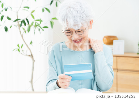 預金通帳を見て考えるシニア女性 預金通帳を見て考えるシニア女性 135514255