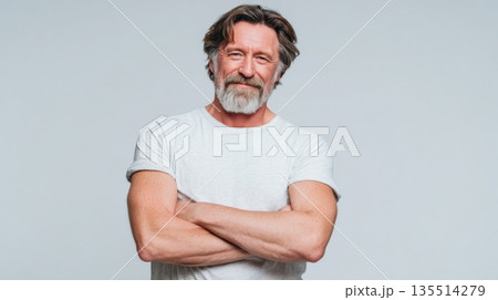 A middle-aged person smiles with pleasant surprise while standing confidently with arms crossed. The background is clean and simple. 135514279