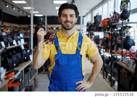 A man worker is holding a drill in a store 135515538