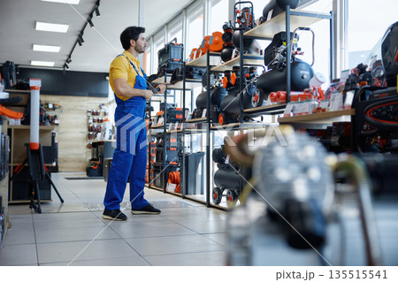 A male worker in a store looking at compressors 135515541