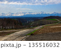 残雪の十勝岳連峰と春の兆しを見せる丘の風景 135516032