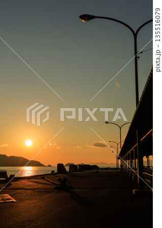 夕焼けに染まる愛媛県八幡浜市 八幡浜港の桟橋と街灯のシルエット 135516079