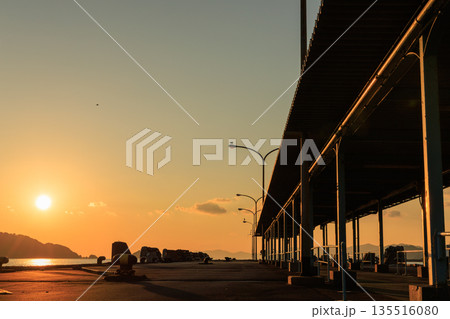 夕焼けに染まる愛媛県八幡浜市 八幡浜港の桟橋と街灯のシルエット 135516080