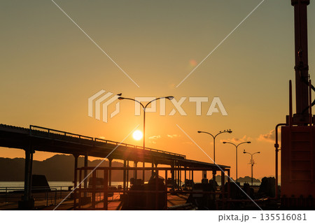 夕焼けに染まる愛媛県八幡浜市 八幡浜港の桟橋と街灯のシルエット 135516081