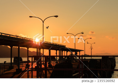 夕焼けに染まる愛媛県八幡浜市 八幡浜港の桟橋と街灯のシルエット 135516092