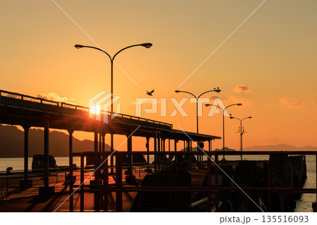 夕焼けに染まる愛媛県八幡浜市 八幡浜港の桟橋と街灯のシルエット 135516093