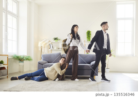 Painful breakup scene with man holding onto woman as she walks away with another Painful breakup scene with man holding onto woman as she walks away with another 135516346