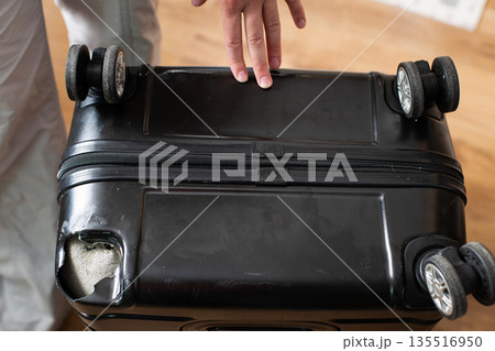 Broken black suitcase with damaged corner showing impact from mishandling at airport 135516950