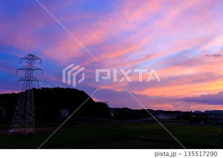 送電鉄塔と田園風景に広がるピンクと紫の幻想的な夕焼け空 送電鉄塔と田園風景に広がるピンクと紫の幻想的な夕焼け空 135517290