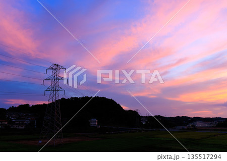 送電鉄塔と田園風景に広がるピンクと紫の幻想的な夕焼け空 送電鉄塔と田園風景に広がるピンクと紫の幻想的な夕焼け空 135517294