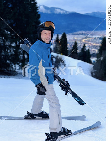 Man skiing at dusk with city view 135518201