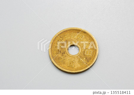 Japanese five yen coin on white surface closeup. 135518411