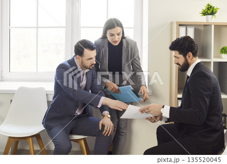 Office businesspeople sitting interacting reviewing contract documents, handing paper, explaining Office businesspeople sitting interacting reviewing contract documents, handing paper, explaining 135520045