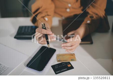 Online payment, Hands of woman holding a credit card and using smart phone for online shopping Online payment, Hands of woman holding a credit card and using smart phone for online shopping 135520811