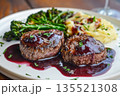 Closeup of appetizing beef fillet medallions topped with berry sauce served with creamy mashed potatoes, bleu cheese and steamed broccoli on white plate 135521308
