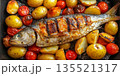 Flat lay of whole grilled trout fish with potatoes and tomatoes baked on coals in black skillet, delicious and healthy dish from seafood 135521317