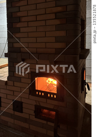 Test fire in the firebox of a heating stove. The open ash door is visible. In semi-darkness. 135521878