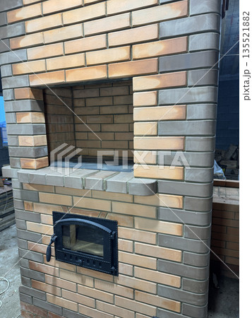 Construction of a heating stove with a cooktop. Doors of the firebox and a niche with the cooktop are visible. Construction of a heating stove with a cooktop. Doors of the firebox and a niche with the cooktop are visible. 135521882
