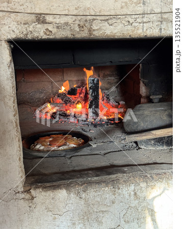 Cooking pizza in a Russian stove next to coals and burning firewood. Turning the pizza pan with a stove hook. Cooking food in a vintage stove. Vertical video. Cooking pizza in a Russian stove next to coals and burning firewood. Turning the pizza pan with a stove hook. Cooking food in a vintage stove. Vertical video. 135521904