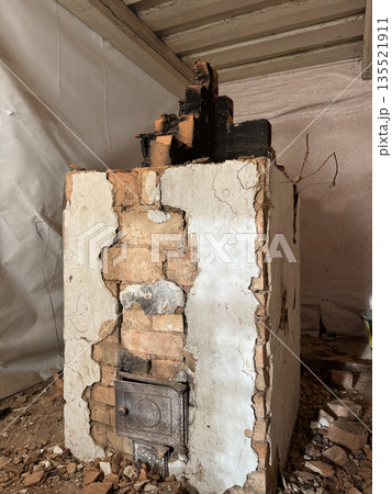 Dismantling a vintage stove in an old house. The firebox door and ash door are visible. The stove is in an emergency condition. 135521911