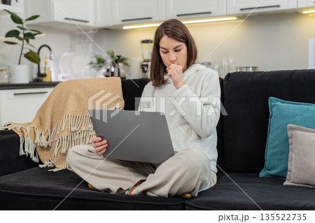 Young woman completes online exam on laptop reads questions selects answers taps Submit feels relief 135522735