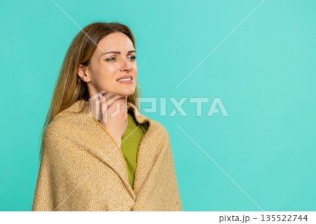 Woman wearing blanket touching throat opening mouth feeling pain while swallowing from cold or flu Woman wearing blanket touching throat opening mouth feeling pain while swallowing from cold or flu 135522744